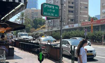 רחוב ז'בוטינסקי פינת ביאליק, מכוניות עוצרות לפני מעבר חצייה להולכת רגל בחולצה לבנה