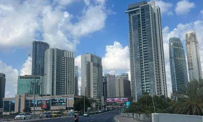 מתחם הבורסה ליהלומים. בניינים גבוהים לכל רוחב התמונה. בחזית בניין הכניסה למרכז היהלומים העולמי. לפני הבניין רחוב אבא הלל סילבר בו שני מסלולים ושדרה ביניהם. מכוניות ואופנוע בכביש.
