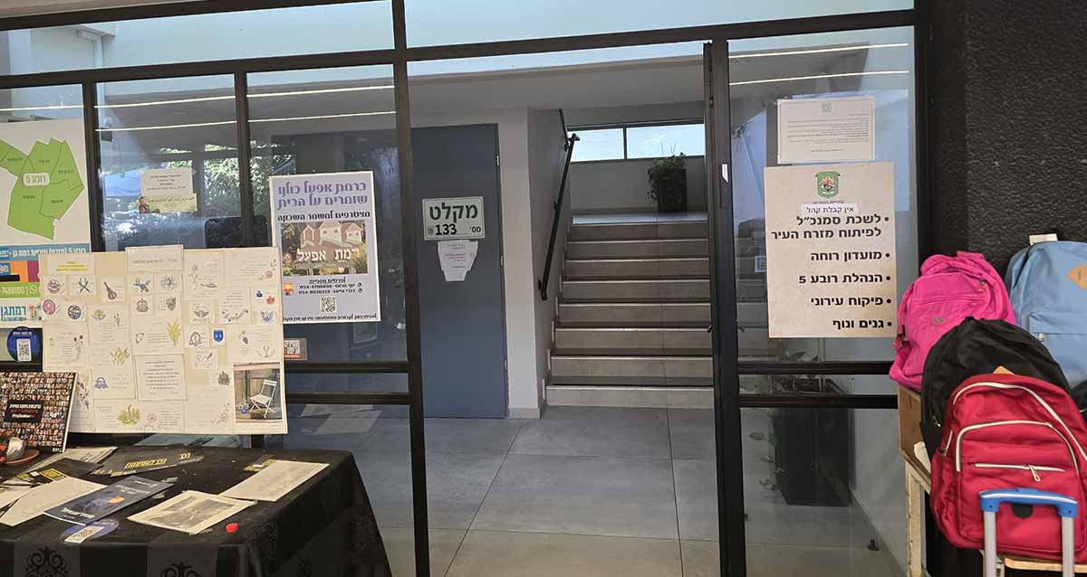 רמת אפעל בניין המשרדים, צילום פנים הבניין. קיר ודלת זכוכית בכניסה. ממול מדרגות לקומה שנייה. בצד ימין של הכניסה על לוח הזכוכית שלט עם רשימת המשרדים: לשכת סמנכ