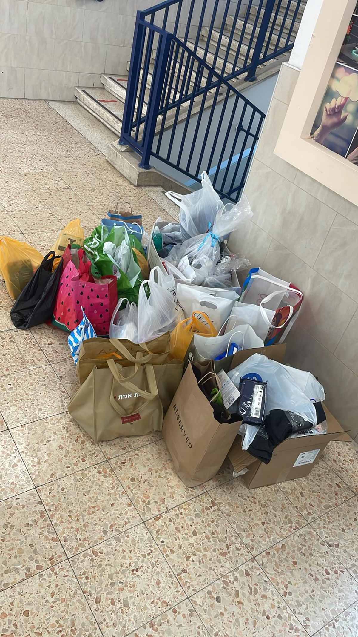 גבעתיים מתגייסת למען חטיבה 188. כ-20 שקיות נייר ושקיות פלסטיק עם מצרכים לחיילים, מונחות על הרצפה.