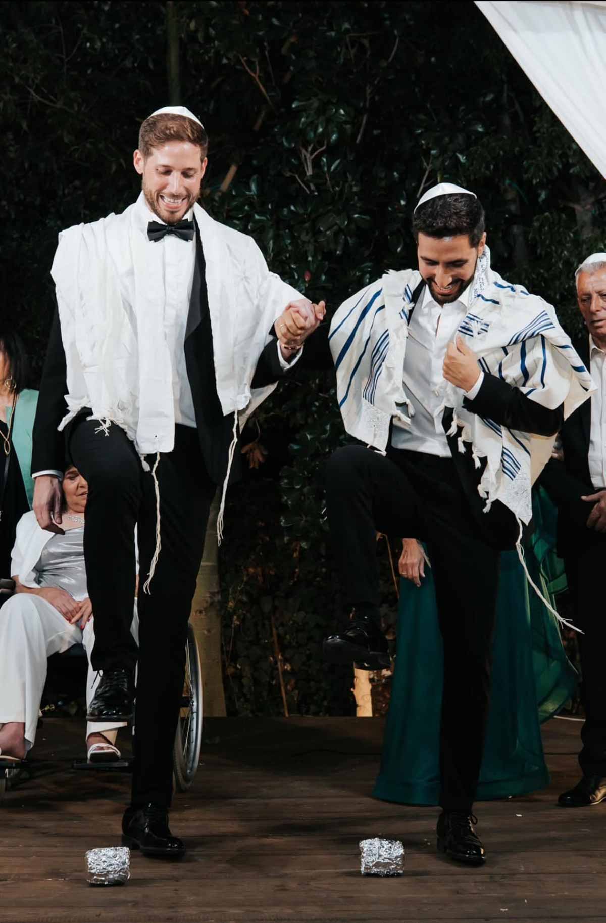 סגן ראש העיר ישראל זרי עם ניב הולנדר, בחליפות שחורות עם טליתות וכיפות לבנות מרימים רגל ימין לשבירת כוס בחתונתם.