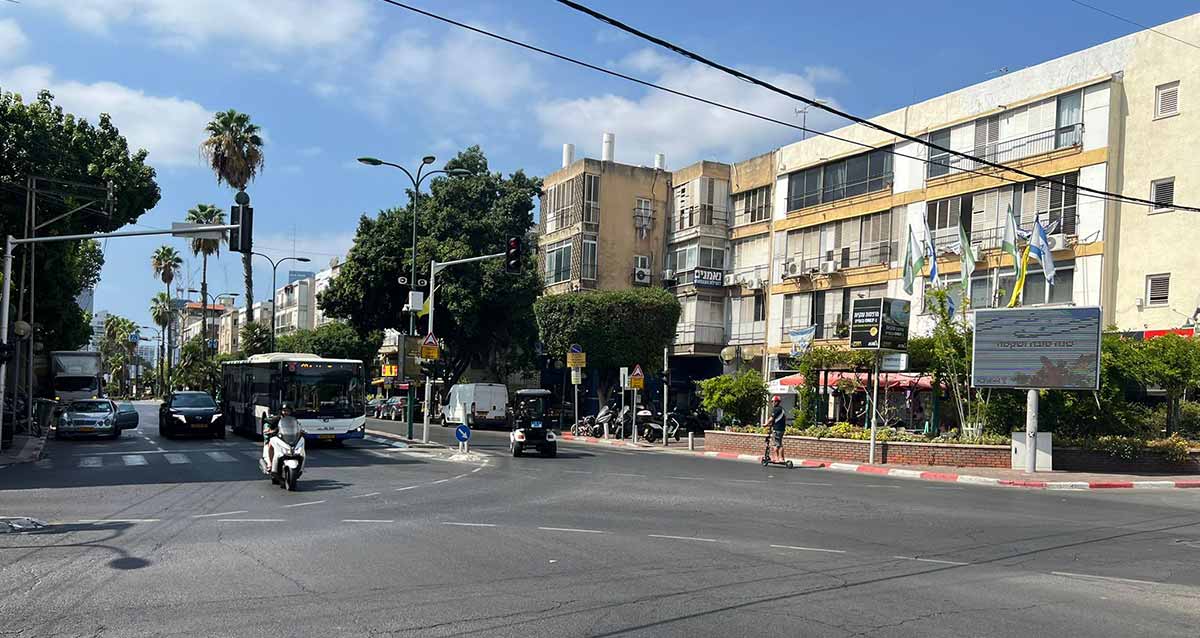 צומת כצנלסון בגבעתיים, רחוב כצנלסון בן שני מסלולים ושניים שלושה נתיבים בכל מסלול. בתים בני 4 קומות לאורך הרחוב. בצומת המרומזר עומד אוטובוס ומכוניות פרטיות. אופנוע עובר את הצומת. בשדרה בין המסלולים עצי דקל.