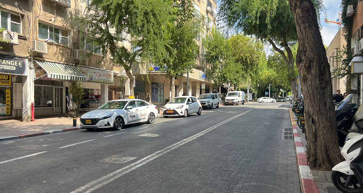רחוב שינקין בגבעתיים. רחוב בן שלושה נתיבים. בנתיב השמאלי חונות מכוניות באדום לבן. משמאל מדרכה ואחריה בניינים גבוהים עם חנויות מקורות בקומת הקרקע. בשמאל חנות CHANGE ולידה חנות עם פרגולה. מימינה חנות בשם מגי-בר. בבניין המרכזי סניף של בנק לאומי.
