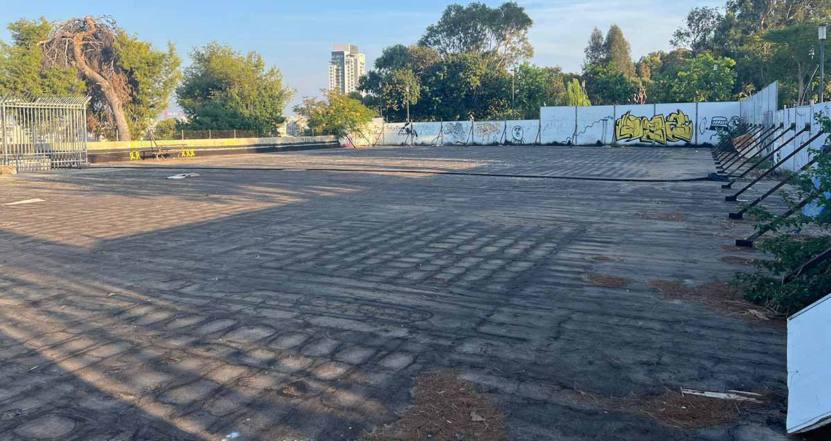 מאגר מים בגן הקופים. מגרש שטוח וגדול עם גדר מתכת מסביב.