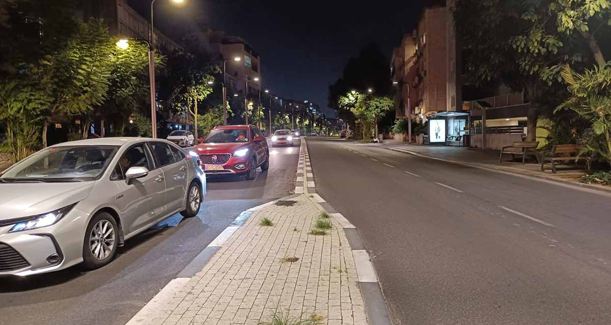 מרוץ מכוניות ברחוב הירדן בלילה. שורת מכוניות פרטיות עם אורות.