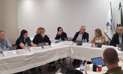 ישיבת מועצת העיר גבעתיים. סביב שולחן בצורת האות ח' המכוסה במפה לבנה, יושבים חברי המועצה. צילום של ראש השולחן בו יושב ראש העיר רן קוניק. על השולחן טאבלטים ובקבוקי שתייה.