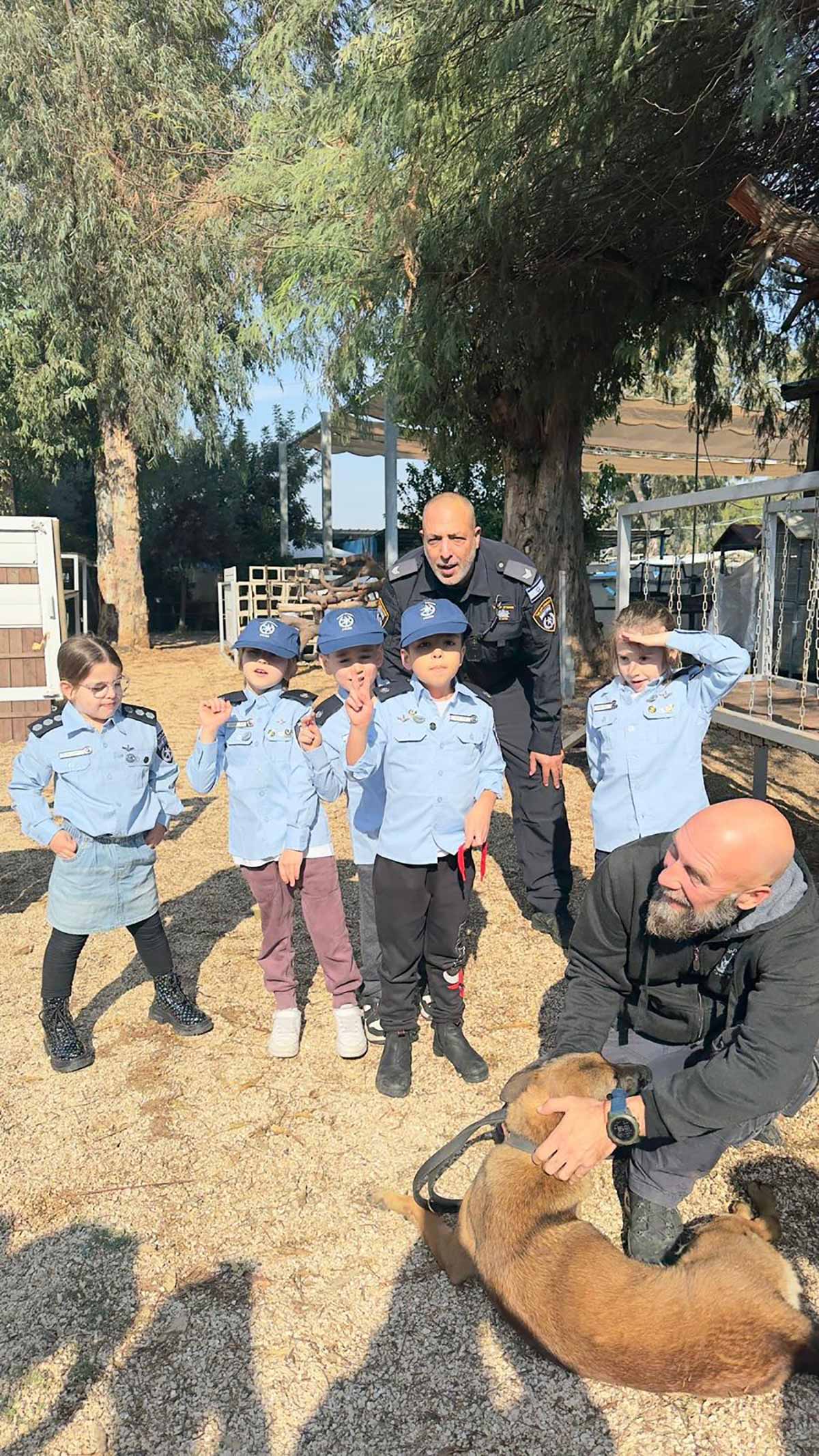 שוטר ליום אחד במשטרת גבעתיים. ילדים עומדים במדי שוטרים עם שוטר מאחוריהם, ואדם אחד יושב עם כלב.