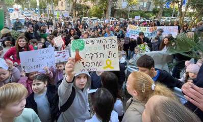 הפגנה נגד עיריית גבעתיים. ילדים עומדים עם שלטים. על שלט קרוב כתוב: זה הששורשים שלנו! אל תעקרו אותם! בי"ס גורדון. ולידו שלט קטן עם הכיתוב: אסור להרוס את הגן המתמטי !