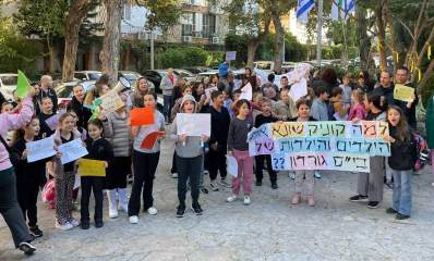 הפגנה נגד עיריית גבעתיים. ילדים והורים עומדים עם שלטים. על שלט גדול בחזית כתוב: למה קוניק שונא את הילדים והילדות של בי"ס גורדון.