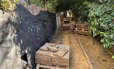 עבודות תשתית בשדרות אפיקים. אבני המדרכה פורקו והן מונחות בערימה. משמאל יריעה שחורה על הגדר של החצר. מימין למדרכה שיחים ועצים.