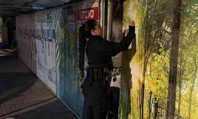 צו סגירה לאתר בנייה ברמת גן. שוטרת מדביקה את הצו עם הקיר המקיף את האתר.