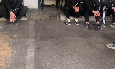 שישה שב"חים נעצרו בעסק בשיפוצים בגבעתיים. השב"חים יושבים עם ידיים אזוקות ובצד ימין יושב שוטר.