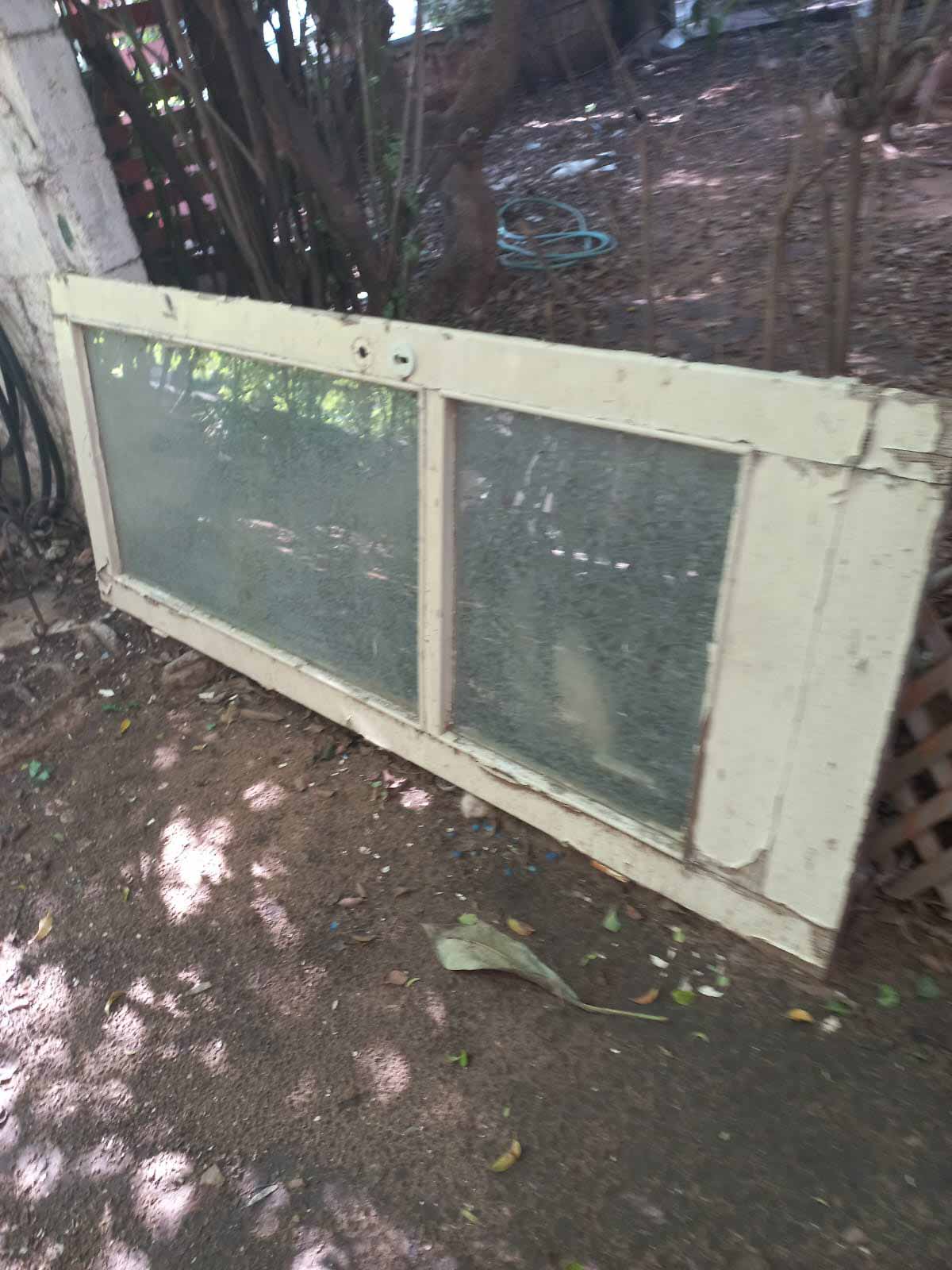 הזנחה ברחוב הרא"ה ברמת גן. דלת עץ בחצר, המחולקת לשלושה חלקים, שניים עם זכוכית.