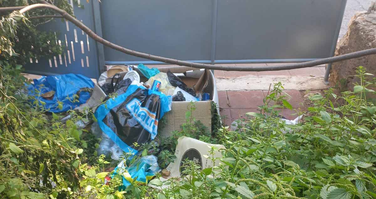 הזנחה ברחוב הרא"ה ברמת גן. שקיות פלסטיק עם אשפה בחצר. קרטון עם אשפה בתוכו.