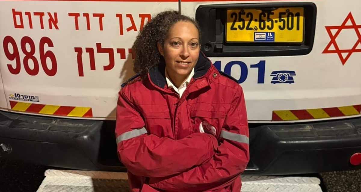 יפעת איל במגן דוד אדום יושבת על אמבולנס בצד האחורי שלו.