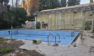 בריכת רמב"ם בגבעתיים. הבריכה ריקה ממים. המבנה פרוץ. פח אשפה על שפת הבריכה.