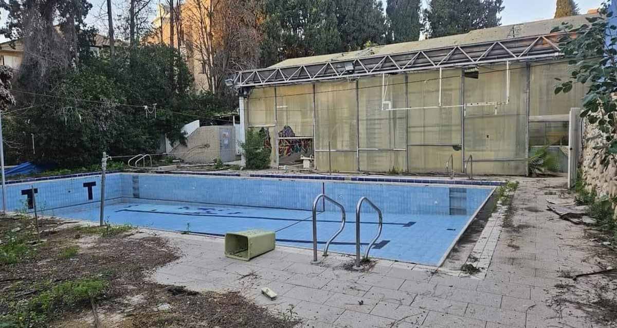 בריכת רמב"ם בגבעתיים. הבריכה ריקה ממים. המבנה פרוץ. פח אשפה על שפת הבריכה.