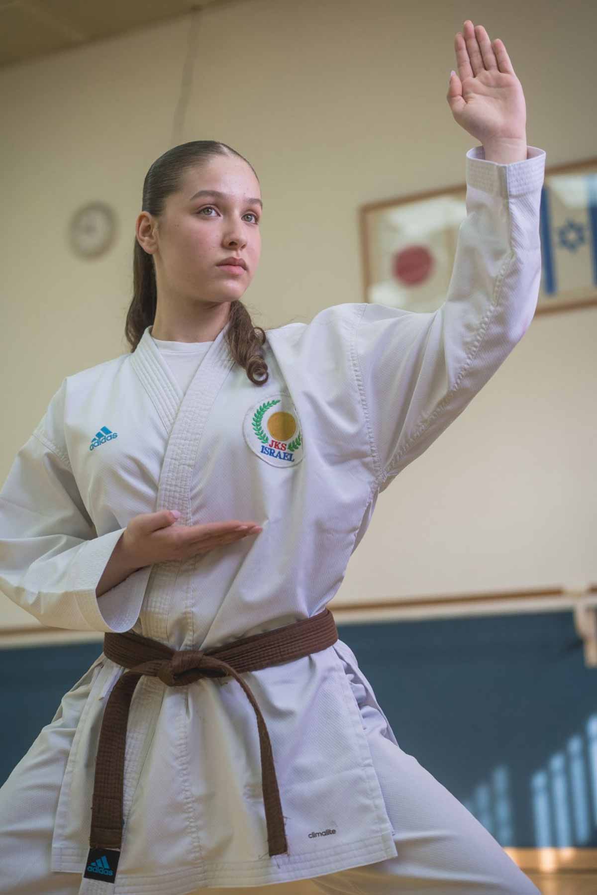 שירה פיליפ אלופת ישראל בקראטה בתלבושת לבנה וחגורה חומה עומדת בתנוחה מקצועית.