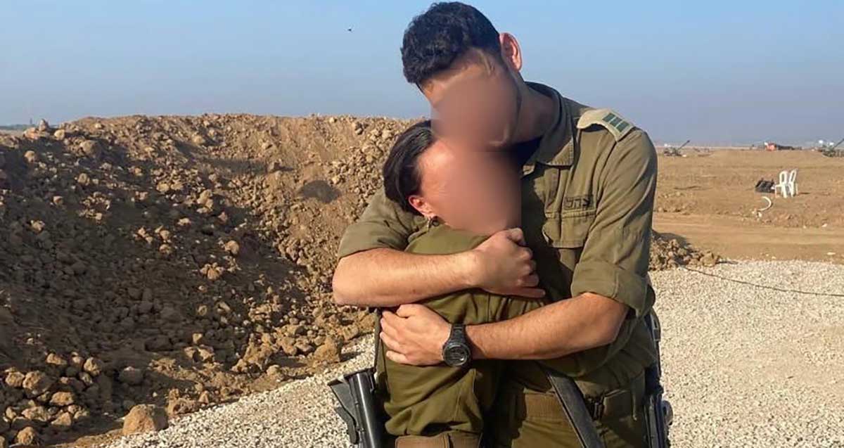 שמונה שנים של זוגיות ויותר מ-550 ימי מילואים יחד. הזוג במדים עם נשק עומדים מחובקים בשטח, והפנים מטושטשות.