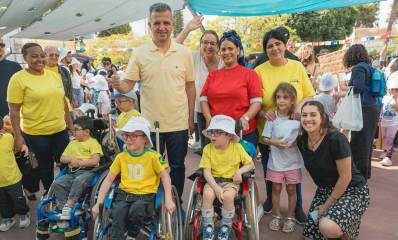 אולימפיאדת גני הילדים ברמת גן. שלושה ילדים על כסאות גלגלים ואחריהם עומד ראש העיר וההורים וילדים נוספים.