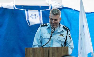 נצ"מ אלעד קליין מפקד מרחב דן עומד לפני דוכן נואמים ומיקרופון לפניו. מאחוריו דגל המדינה.