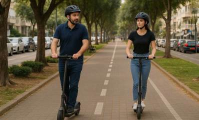 רוכב ורוכבת בקורקינטים חשמליים בשדרה רחבה בין שני כבישים.