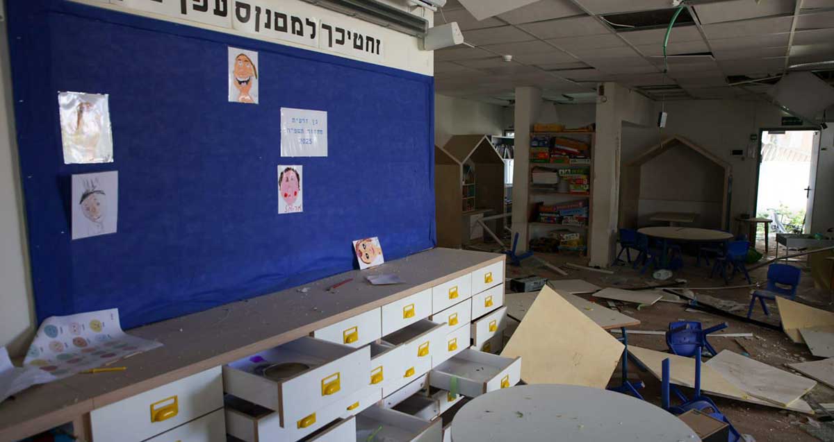 נזק בגן ילדים ברמת גן. התקרה מלוחות גבס שבורה. על הרצפה שברים, כיסאות הפוכים, ומגירות פתוחות בארונית המגירות.