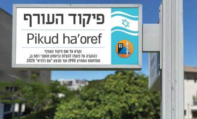 הצעה לקרוא רחוב שנהרס בר"ג על שם פיקוד העורף. תמונה של השלט בעברית: פיקוד העורף, באנגלית:Pikud ha'oref, ומתחת לשם הכיתוב: נקרא על שם פיקוד העורף כהוקרה על פועלו להצלת והיטחון תושבי רמת גן, ממלחמת המפרץ 1990 ועד מבצע "עם כלביא" 2025. בצד ימין של השלט דגל המדינה וסמל עגול של פיקוד העורף.