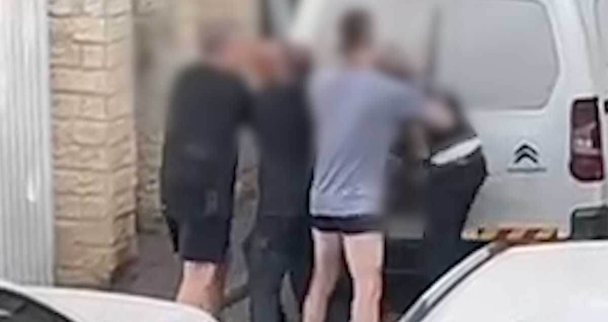 חבורה (פנים מטושטשות). מתקוטטת מאחורי רכב מסחרי ברחוב