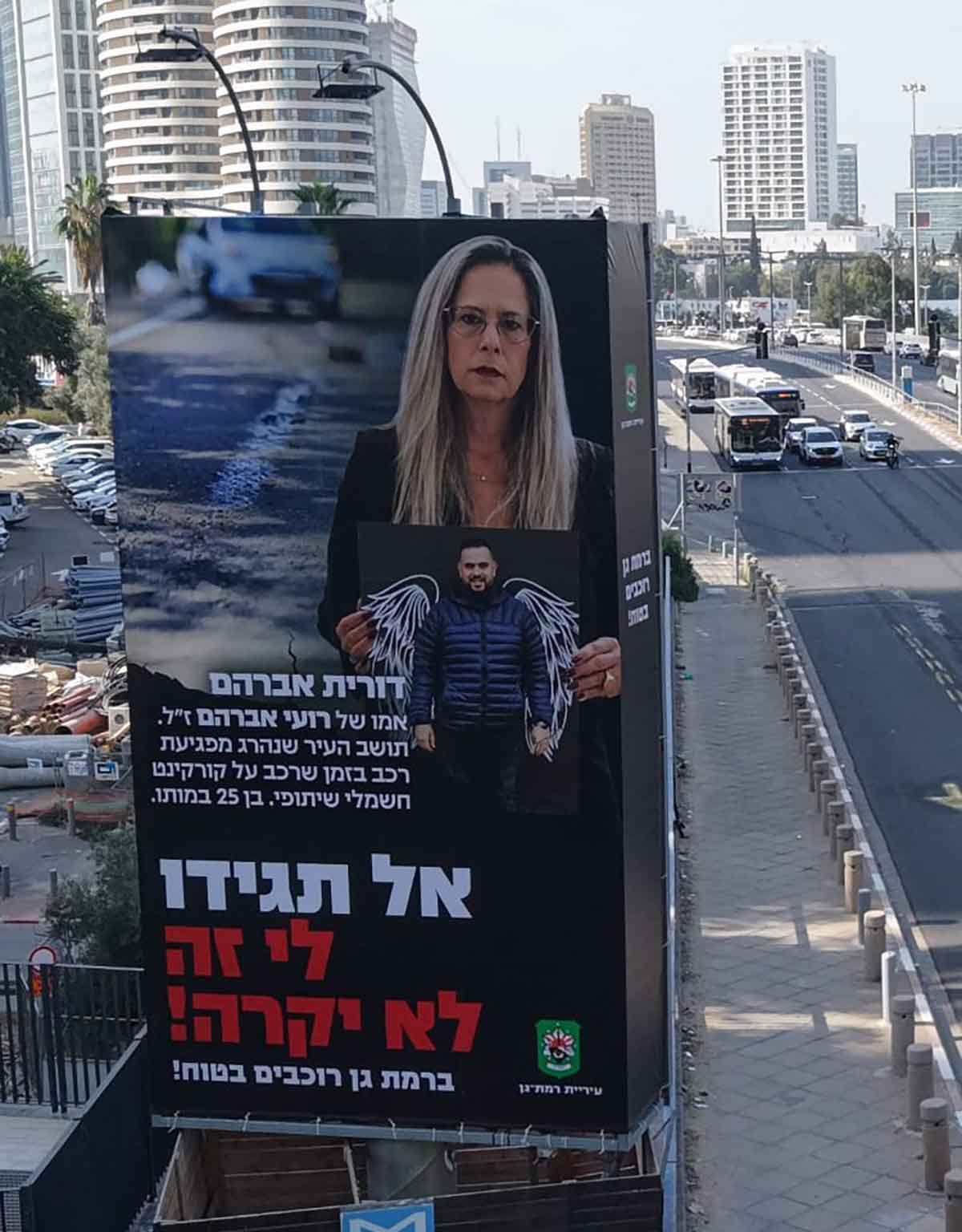 שלט חוצות לחודש הבטיחות בדרכים ברמת גן. תמונה של דורית אברהם אמו של רועי אברהם ז"ל, וכיתוב: תושב העיר שנהרג מפגיעת רכב בזמן שרכב על קורקינט חשמלי שיתופי, בן 25 במותו. אל תגידו לי זה לא יקרה! ברמת גן רוכבים בטוח!