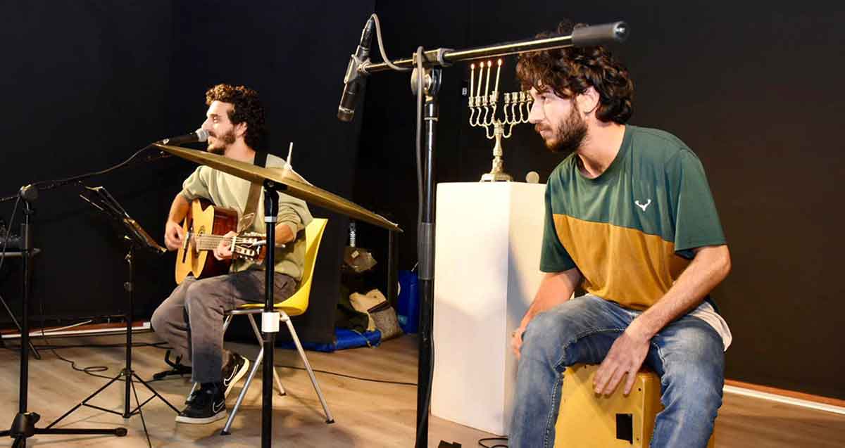 אירוע הדלקת נרות למשפחות שכולות ברמת גן. על במה יושבים שני אמנים, אחד מתופף ואחד עם גיטרה.