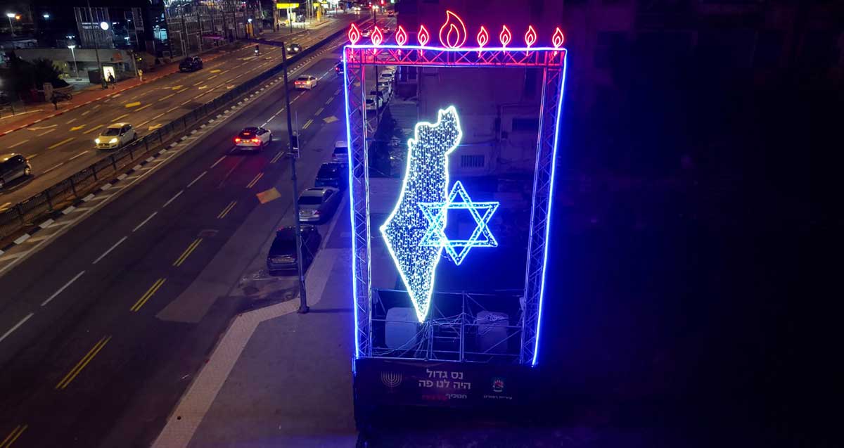 חנוכיית הניצחון. שלט מאור לדים ברמת גן של חנוכיה ומתחתיה מפת ישראל ומגן דוד. מתחת כיתותב. נס גדול היה לנו פה