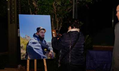 חניכת ספסל הנצחה ע"ש ניב תל צור ז"ל ברמת גן. חצובת ציור עם תמונתו ואימו מצלמת את תמונתו. האב מאחור.