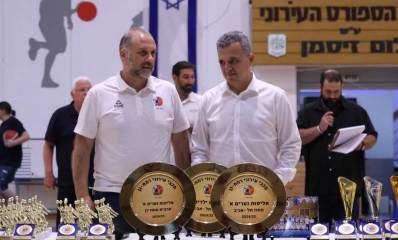 כרמל שאמה הכהן וחן שניידרמן ליד שולחן צלחות אליפות וגביעים