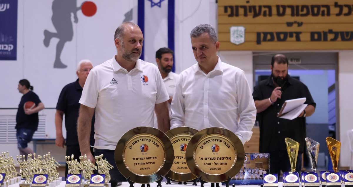 כרמל שאמה הכהן וחן שניידרמן ליד שולחן צלחות אליפות וגביעים