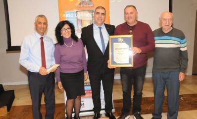 סניף גבעתיים של האגודה לתרבות הדיור נבחר למצטיין המחוזי. אישה וארבעה גברים בתמונה קבוצתית. אחד אוחז תעודה ממוסגרת.