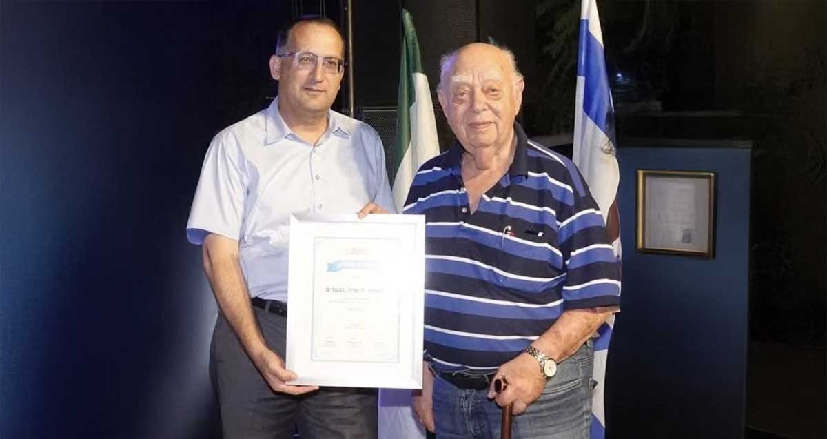 אפרים פרי הר ורן קוניק. רן קוניק אוחז בידו תעודה.