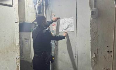 שוטר מדביק צו סגירה על דלת מתכת
