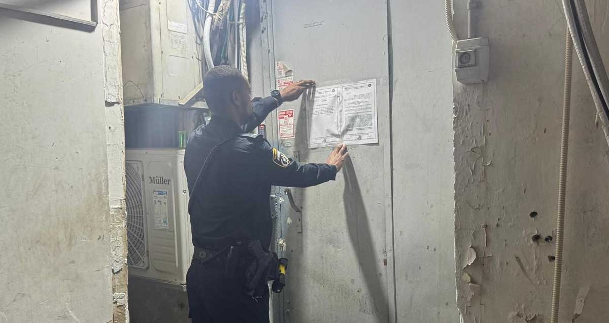 שוטר מדביק צו סגירה על דלת מתכת