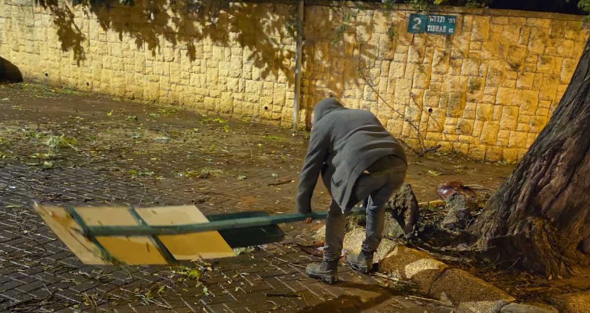 עובד עירייה מפנה שלט שנעקר בסופה