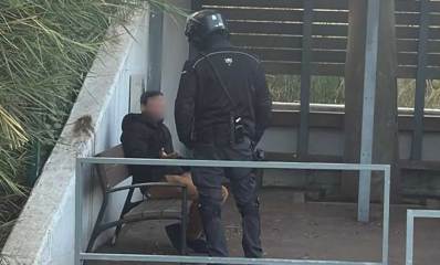 גבר מטריד בשכונת החרוזים ברמת גן. הגבר יושב על ספסל ולידו עומד שוטר. פני הגבר מטושטשים.