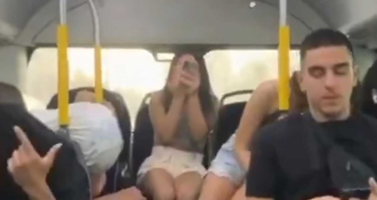 נערות ונער בחלק האוחרי של אוטובוס עם טלפונים ניידים