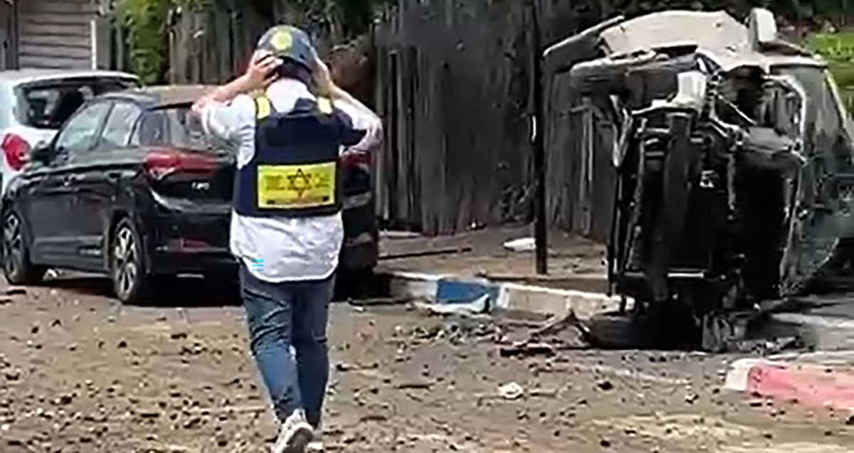 איש איחוד הצלה עם קסדה על ראשו ליד רכב מפוייח והפוך ושברים ברחוב בגבעתיים