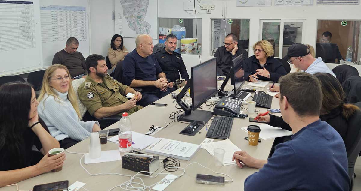 הערכת מצב בגבעתיים. אנשי העירייה, משטרה ופיקוד העורף יושבים סביב שולחן. מסכים על השולחן.