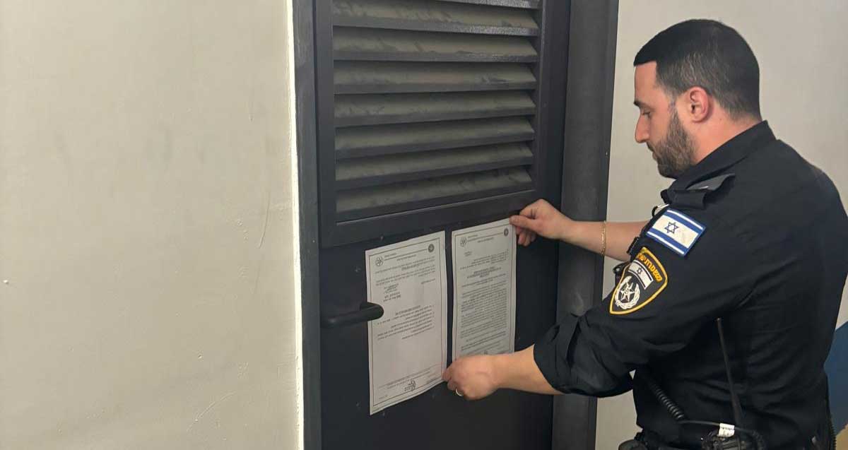 צו סגירה של המחסן בו אותרו סמים ברמת גן. שוטר מדביק את הצו על דלת המתכת של המחסן.