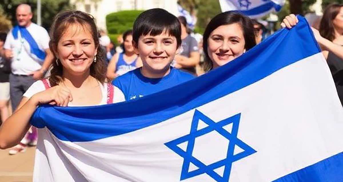 הדמיה AI של חגיגות יום העצמאות. שתי נערות אוחזות בדגל ישראל וילד בין שתיהן.