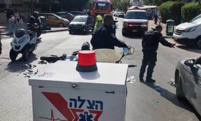 אופנוען נפצע קשה בתאונת דרכים ברמת גן. אופנוע על הכביש ולידו אנשי הצלה עם אופנוע של ארגון הצלה.