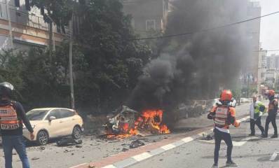 פגיעת טיל ורכב שרוף ברחוב בן גוריון ברמת גן. צוותי כבאות והצלה מסביב לרכב השרוף