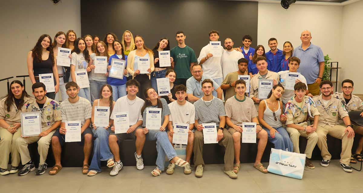 אירוע הוקרה ליוצאים למכינות ולשנת שירות בגבעתיים. המתנדבים יושבים ועומדים לצילום קבוצתי עם תעודה ביד.