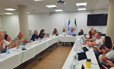 ישיבת מועצת העיר גבעתיים. חברי המועצה מסובים לשולחן ארון בצורת ח